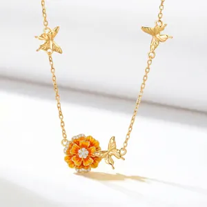 Detailed view of a gold plated copper birth flower necklace with orange enamel and butterflies.