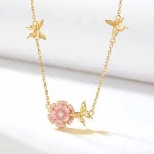 Detailed macro view of gold necklace featuring a pink enamel flower and butterfly charms