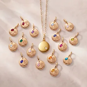 Macro view of gold birth flower charms with colorful gemstones on a textured marble background