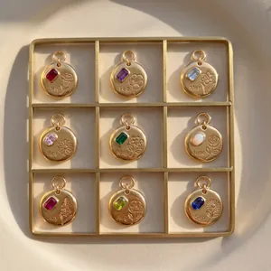 Detail showing nine gold birth flower pendants with colorful gemstones in a display tray