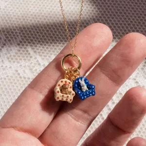 Macro detail view of adorable cartoon bear and rabbit sofa pendants on a gold chain