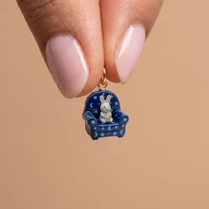 Detailed close-up of a tiny rabbit sitting in a blue star-patterned sofa charm