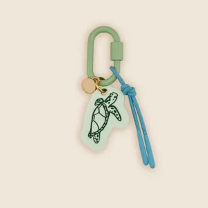 Detail view of retro hand-drawn sea turtle charm on light green carabiner and blue cord