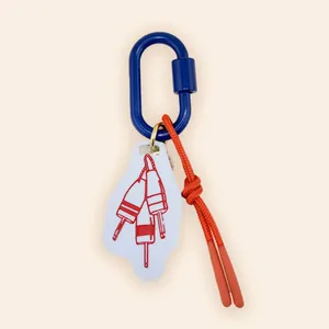Close-up of nautical buoy bag charm featuring blue carabiner and red braided rope
