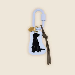 Detail view of a retro style bag charm featuring a black Labrador silhouette on a white tag