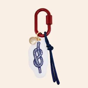 Detailed view of nautical bag charm featuring a blue rope knot on a white acrylic tag.