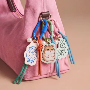 Close-up of cute acrylic animal charms with colorful cords and pearls on a pink bag