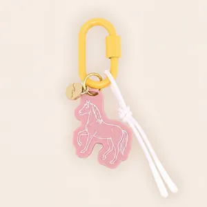 Detailed macro view of a cute pink acrylic horse bag charm with yellow carabiner