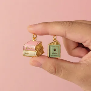 Nahaufnahme von Vintage-Emaillebuch-Anhängern aus rosa und grünem Edelstahl Schmuck