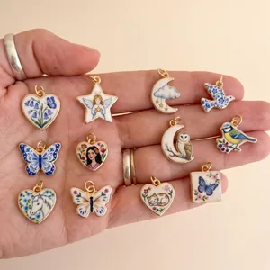 Close-up of various fairytale-themed animal and heart pendants held in hand for jewelry.