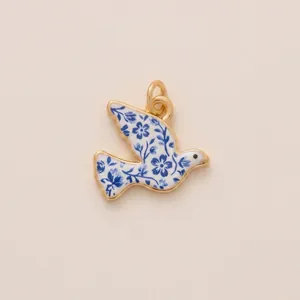 Close-up of a bird-shaped pendant with blue and white floral patterns and gold frame.