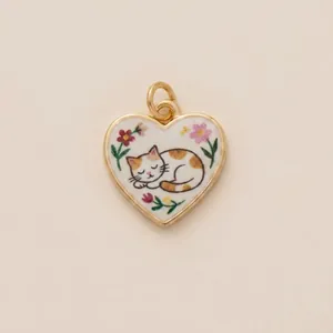 Detailed close-up of a heart-shaped gold pendant featuring an embroidered sleeping cat design