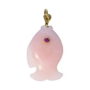 Close-up of a pink carved fish pendant featuring a magenta gemstone eye and gold bail