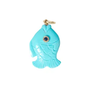 Macro view of a turquoise-colored fish pendant with blue gemstone eye