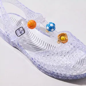 Macro detail of 3D enamel sports ball shoe charms attached to a glittery jelly sandal