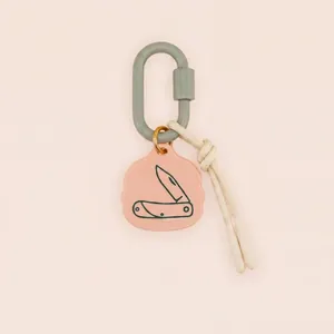 Vue rapprochée du motif couteau de camping sur l'étiquette du porte-clés rose.