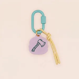 Gros plan d'un charme de hache en acrylique violet sur un porte-clés mousqueton turquoise