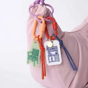 Detail showing furniture-themed acrylic charms and colorful carabiners on a pink bag