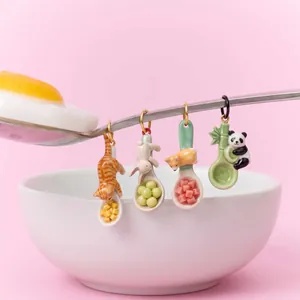 Dettaglio di ciondoli a cucchiaio con animali in miniatura: gatto, coniglio e panda.
