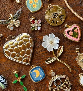 Dettaglio macro di vari ciondoli vintage placcati in oro su superficie in legno rustico