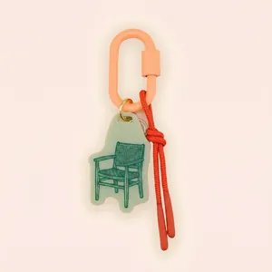 Detail of chair pendant keychain with orange carabiner and red cord accent.