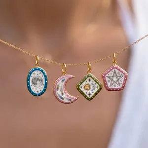 Macro view of detailed celestial enamel pendants featuring moon and sun motifs on gold