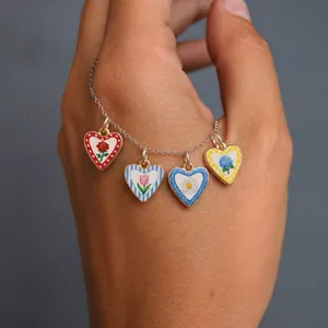 Close-up of four colorful enamel heart-shaped floral pendants on a silver necklace chain