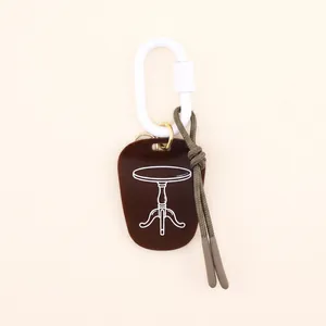 Close-up detail of a minimalist brown acrylic keychain with vintage table line drawing