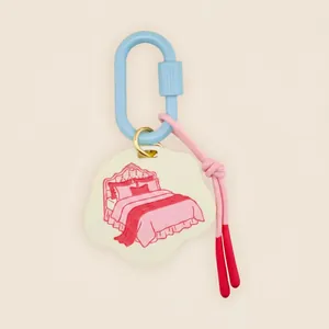 Close-up of a cloud-shaped keychain pendant featuring a red line drawing of a bed motif