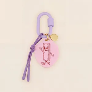 Primo piano di un simpatico ciondolo a forma di righello rosa con moschettone viola