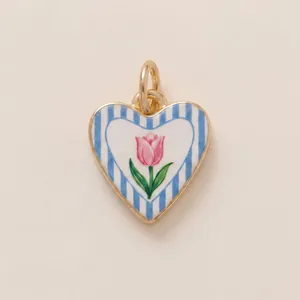 Detailed macro view of gold-plated heart pendant with blue stripes and pink tulip