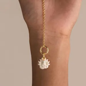 Detailed close-up showing a cute white nine-tailed fox ceramic pendant on a gold chain