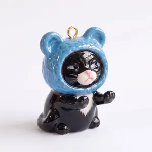 Detail of a cute ceramic black cat charm wearing a blue bear hat for DIY jewelry