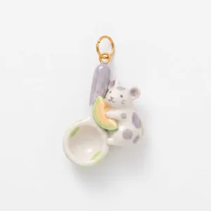Vista dettagliata di un ciondolo in ceramica a forma di topo con melone su un cucchiaio.