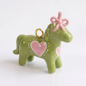 Gros plan d'un pendentif poney en émail vert avec des cœurs roses pour bijoux DIY