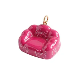 Dettaglio di un ciondolo a forma di divano in smalto rosa con gatti bianchi per gioielli fai-da-te