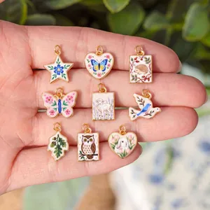Close-up detail of nine vintage hand-painted animal charms with pastoral floral motifs