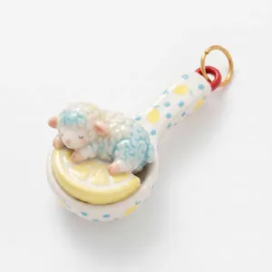 Primo piano di un agnellino di ceramica che dorme su una fetta di limone in un mini mestolo