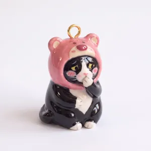 Detailed close-up of a cute ceramic cat charm wearing a pink bear hat for DIY jewelry