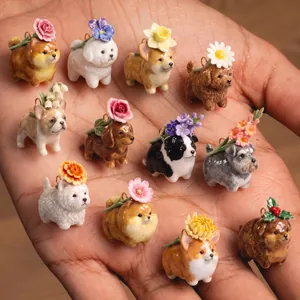 Detailed macro view of various miniature ceramic dog charms with flower headpieces in a palm.