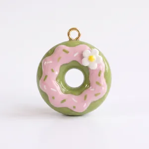 Vue macro d'un pendentif en émail en forme de donut rose et vert avec fleur