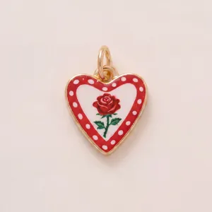 Close-up of heart-shaped copper pendant with red rose illustration and polka dot border