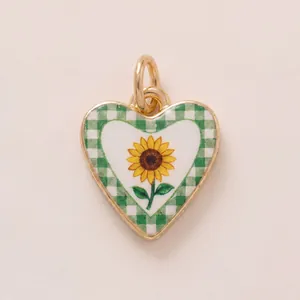 Detail shot of a gold heart pendant with a sunflower and green checkered pattern.