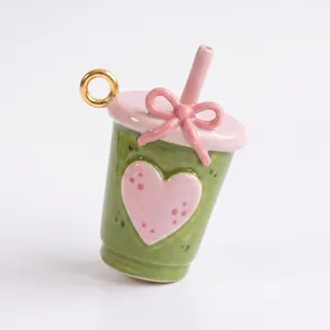Vue macro détaillée d'une breloque en émail vert macaron et rose en forme de tasse