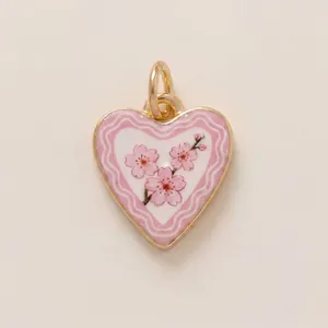 Close-up detail of a pink heart shaped enamel pendant with delicate cherry blossom design
