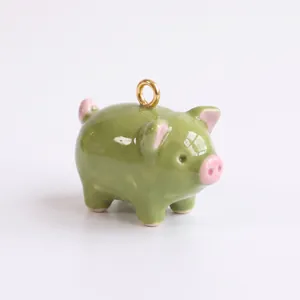 Gros plan d'un charm cochon en émail vert avec des oreilles roses pour bijoux DIY