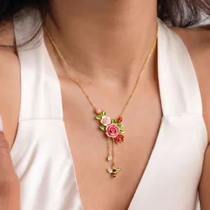 Primo piano di collana floreale smaltata retrò con pendente a rosa e nappa con ape