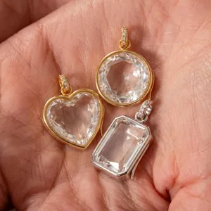 Dettaglio di ciondoli portafoto in cristallo sfaccettato a forma di cuore e tondo.