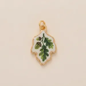 Detail view of a vintage painted oak leaf pendant with acorn motif for DIY jewelry