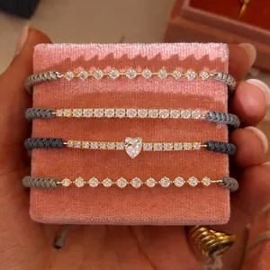 Nahaufnahme von vier geflochtenen Armbändern mit Herz- und Rund-Zirkonia Steinen.